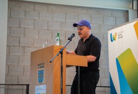 Der Referent Tobias Ginsburg steht am Rednerpult.