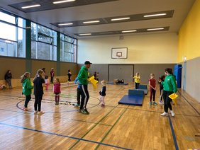 Kinder und Erwachsene in einer Turnhalle mit Spielgeräten