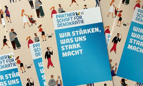 Flyer der Partnerschaft für Demokratie Landkreis Sankt Wendel liegen kreuz und quer auf einem Tisch.