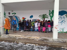 Schüler:innen bemalen eine Wand auf dem Schulhof.
