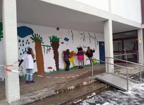 Schüler:innen bemalen die Wand auf dem Schulhof.