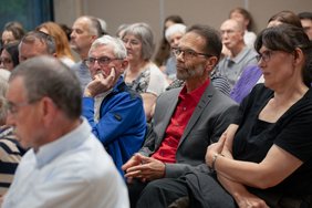 Nahaufnahme von drei Gästen der Veranstaltung, die interessiert zuhören.