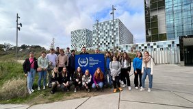 Eine Jugendgruppe an einem Schild, auf dem unter anderem "International Criminal Court" steht.