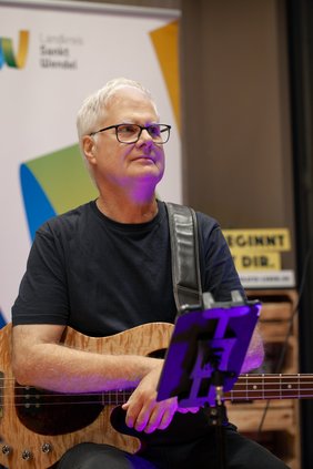 Ein Mitglied der Band Brillant sitzt, den Bass umgeschnallt.