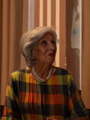 Frau Michalski, in einem bunten Kleid, blickt nach rechts.