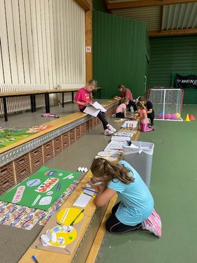 Kinder basteln in einer Tennishalle.