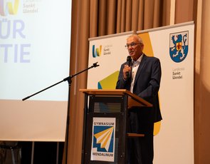 Landrat Udo Recktenwald steht am Rednerpult und hält ein Mikrofon in der Hand
