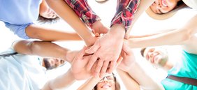 Mehrere Personen legen ihre Hände übereinander.