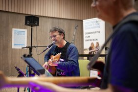 Die Band Brillant spielt sitzend, ein Musiker ist nur ausschnittsweise erkennbar.
