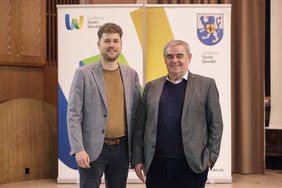 Der Referent Peter Müller und der Kreisbeigeordnete Dennis Meisberger stehen nebeneinander. 