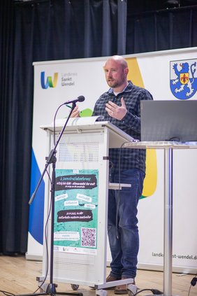 Ein Mann spricht am Rednerpult auf der Bühne