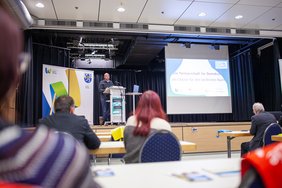 Eine Person steht auf der Bühne und spricht.