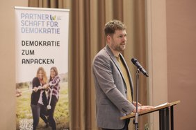 Der Kreisbeigeordnete Dennis Meisberger steht am Rednerpult und spricht.