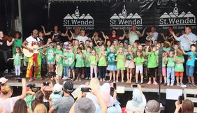 Menschen, darunter viele Kinder, auf einer Bühne.