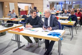 Landrat Udo Recktenwald und der Bürgermeister von Tholey sprechen miteinander am Tisch sitzend.